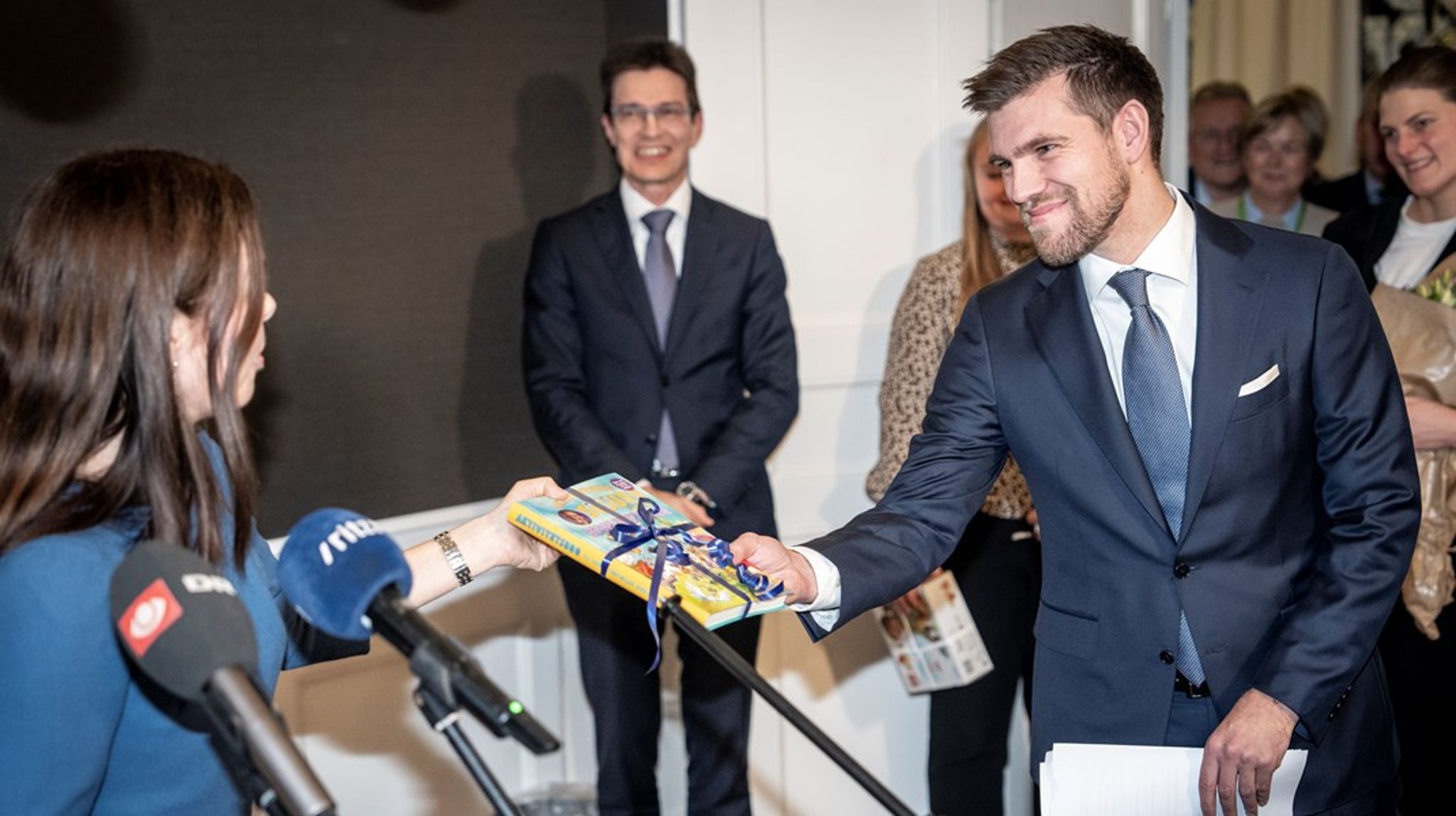 Afgående kirkeminister Louise Schack Elholm giver afløseren Morten Dahlin bogen "Sigurd fortæller bibelhistorier" af Sigurd Barrett i gave.