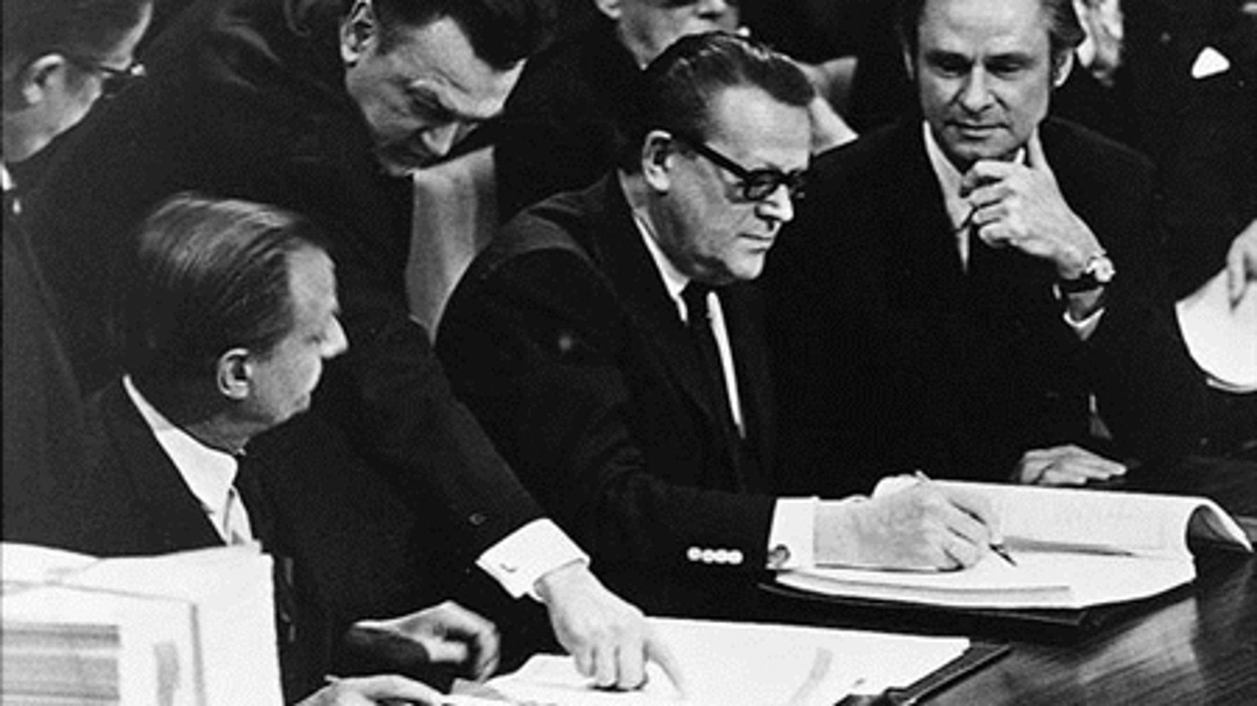 Ivar Nørgaard anvises, hvor han kan skrive under på dansk medlemskab af EF, mens Jens Otto Krag allerede er i sving, og den danske diplomat Jens Christensen overvåger, at alt går rigtigt til.