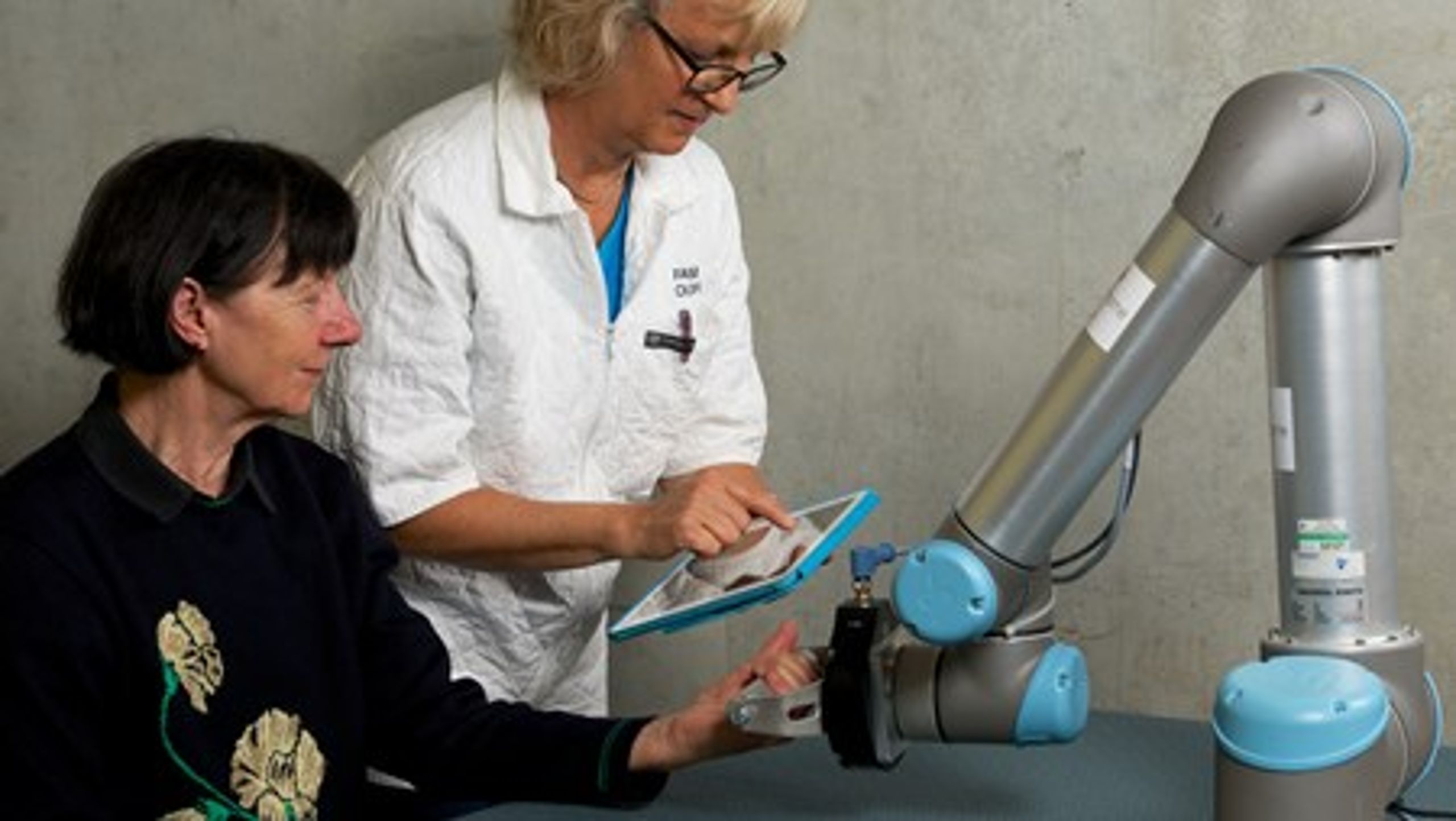 Projektleder i Robocluster Conny Heidtmann instruerer en patient i genoptræning ved hjælp af Syddansk Universitets industrirobot.