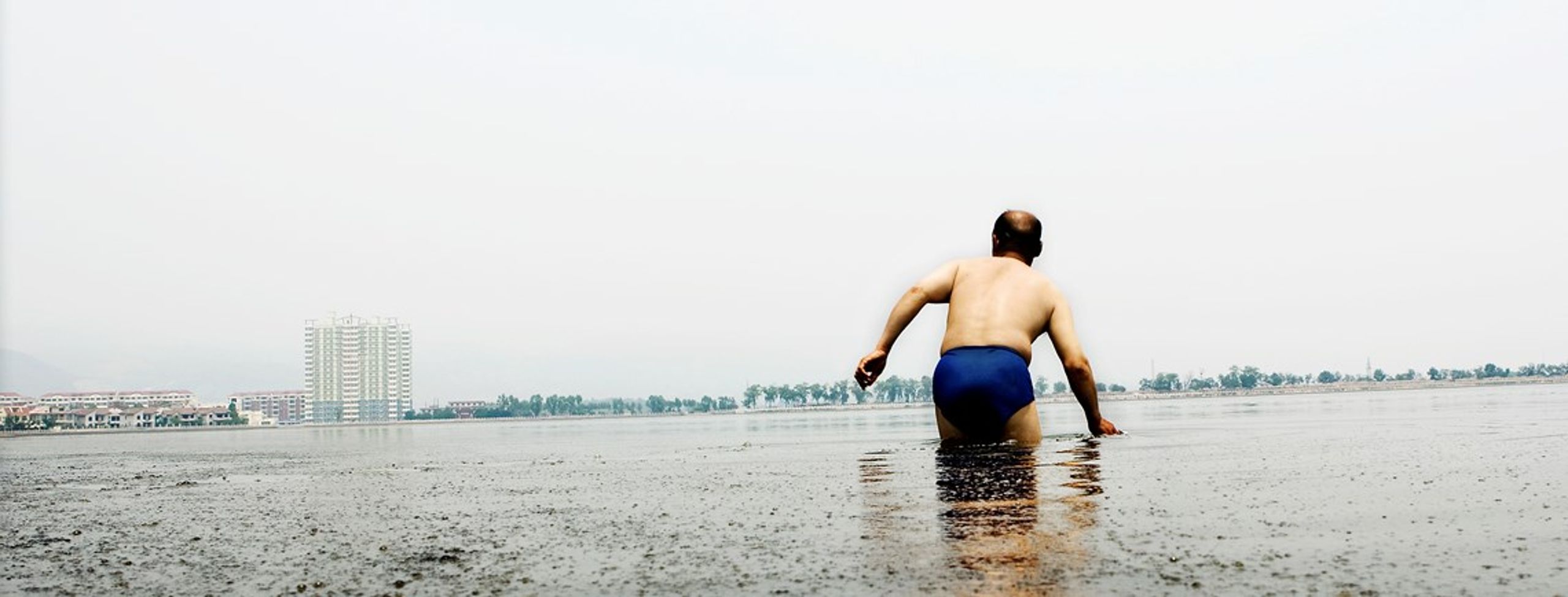 En ældre kinesisk&nbsp;mand tager sig en dukkert i en voldsomt forurenet sø i Shanxi.&nbsp;