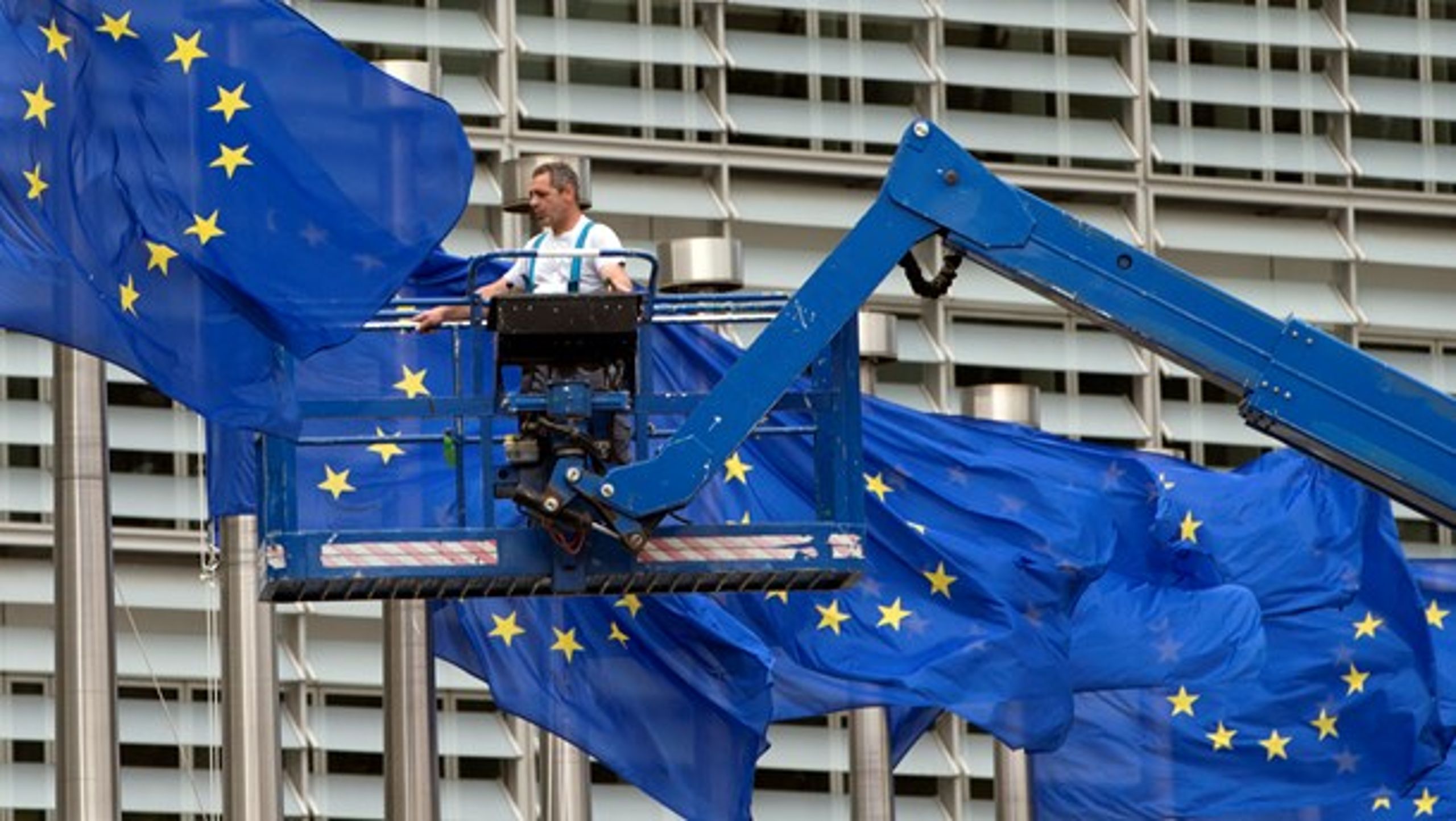 Det danske medlemskab af EU luner på bundlinjen og giver samtidig mulighed for at påvirke store dagsordener som migration, skattesnyd og terrorbekæmpelse, skriver Jan Høst Schmidt. På billedet ses en arbejder, der justerer flagene foran kommissionsbygningen i Bruxelles.&nbsp;