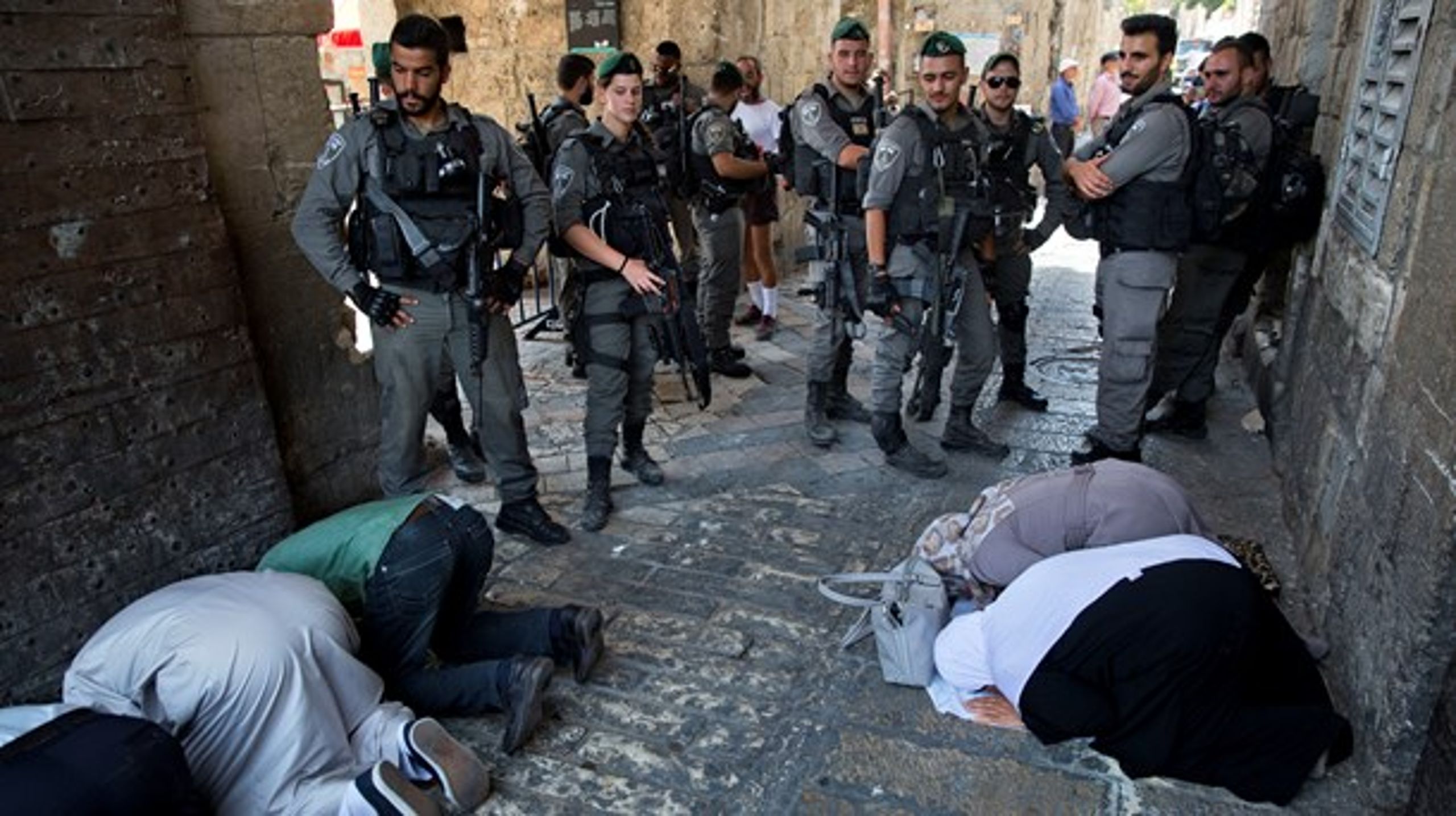 Palæstinensere i bøn, mens det israelske grænsepoliti holder vagt ved Løveporten i Jerusalems gamle bydel.<br>
