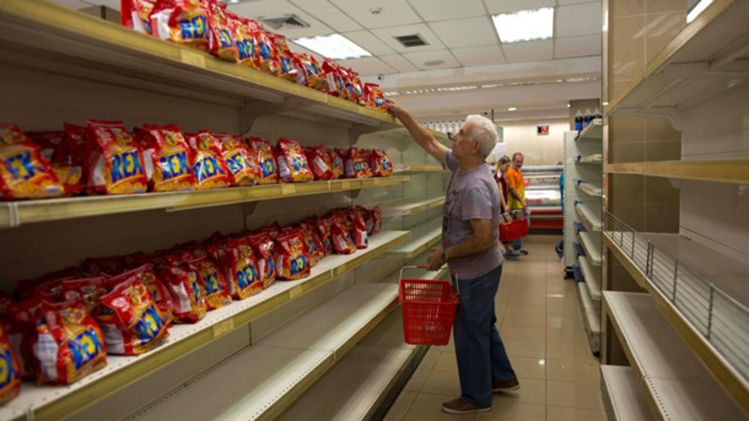 <b>TOMME HYLDER:&nbsp;</b>&nbsp;En mand på indkøb i et supermarked i Caracas, Venezuela, hvor den eneste tilgængelige vare er småkager. [Foto: Ariane Cubillos/Ritzau Scanpix].<br>