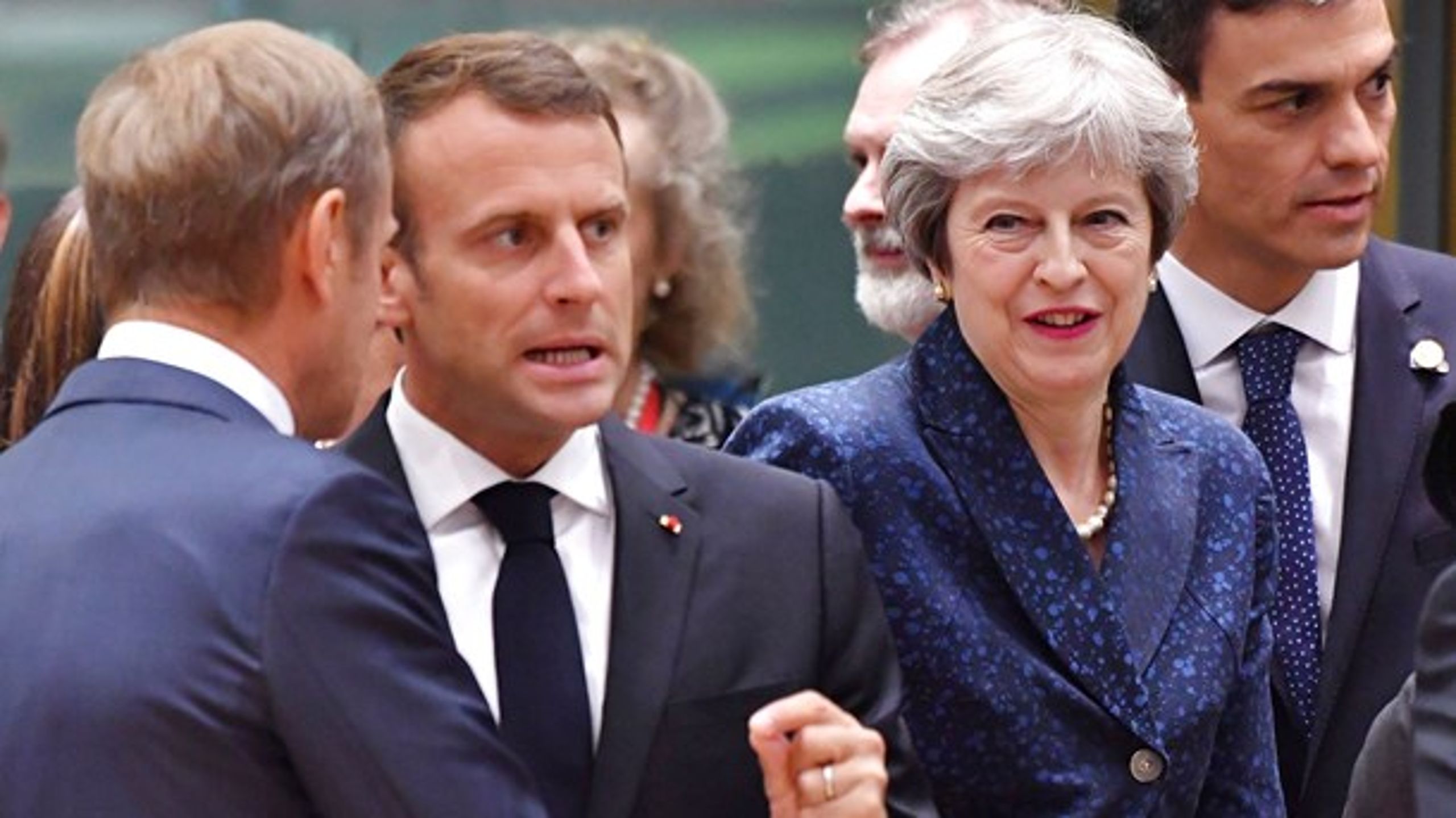 Den britiske premierminister, Theresa May, ser til, men Frankrigs præsident, Emmanuel Macron, og Det Europæiske Råds formand, Donald Tusk, taler under topmødet i Bruxelles.