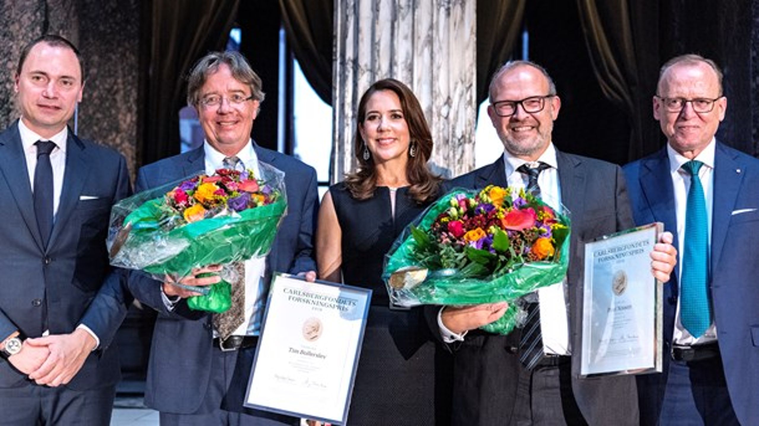 Årets to vindere af Carlsbergfondets Forskningspris,&nbsp;Tim Bollerslev (t.v.) og&nbsp;Poul Nissen (t.h.),&nbsp;flankerer H.K.H. Kronprinsessen.