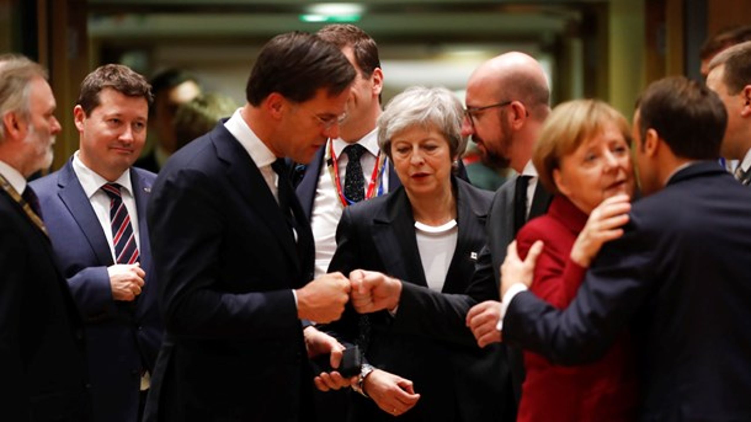 Den britiske premierminister, Theresa May, er omringet af sine hollandske og belgiske kolleger, mens den tyske kansler og franske præsident kindkysser i forgrunden.