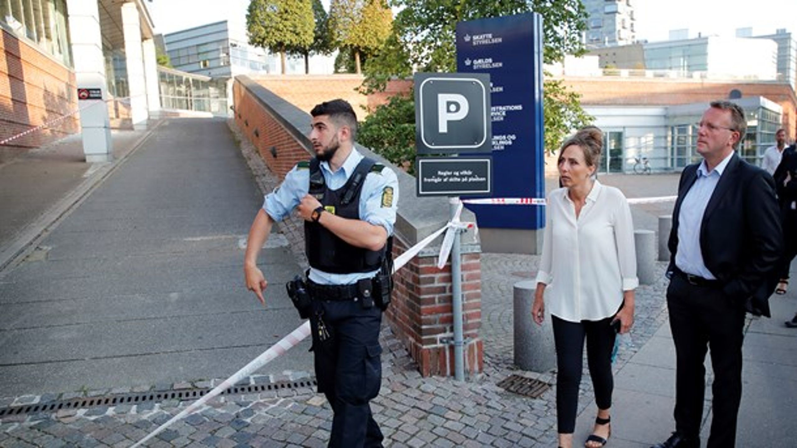 En rystet direktør fra Skattestyrelsen og skatteminister Morten Bødskov (S) flankeret af en betjent på arbejde&nbsp;efter eksplosionen ved Skattestyrelsen 6. august.