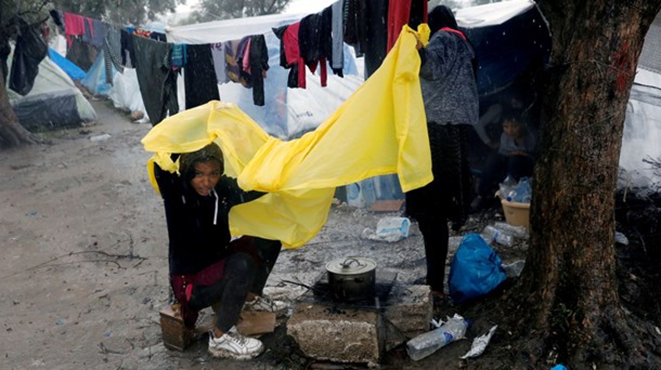 Ung pige, der skærmer sig mod regnen, uden for flygtningelejren Moria på den græske ø Lesbos.&nbsp;
