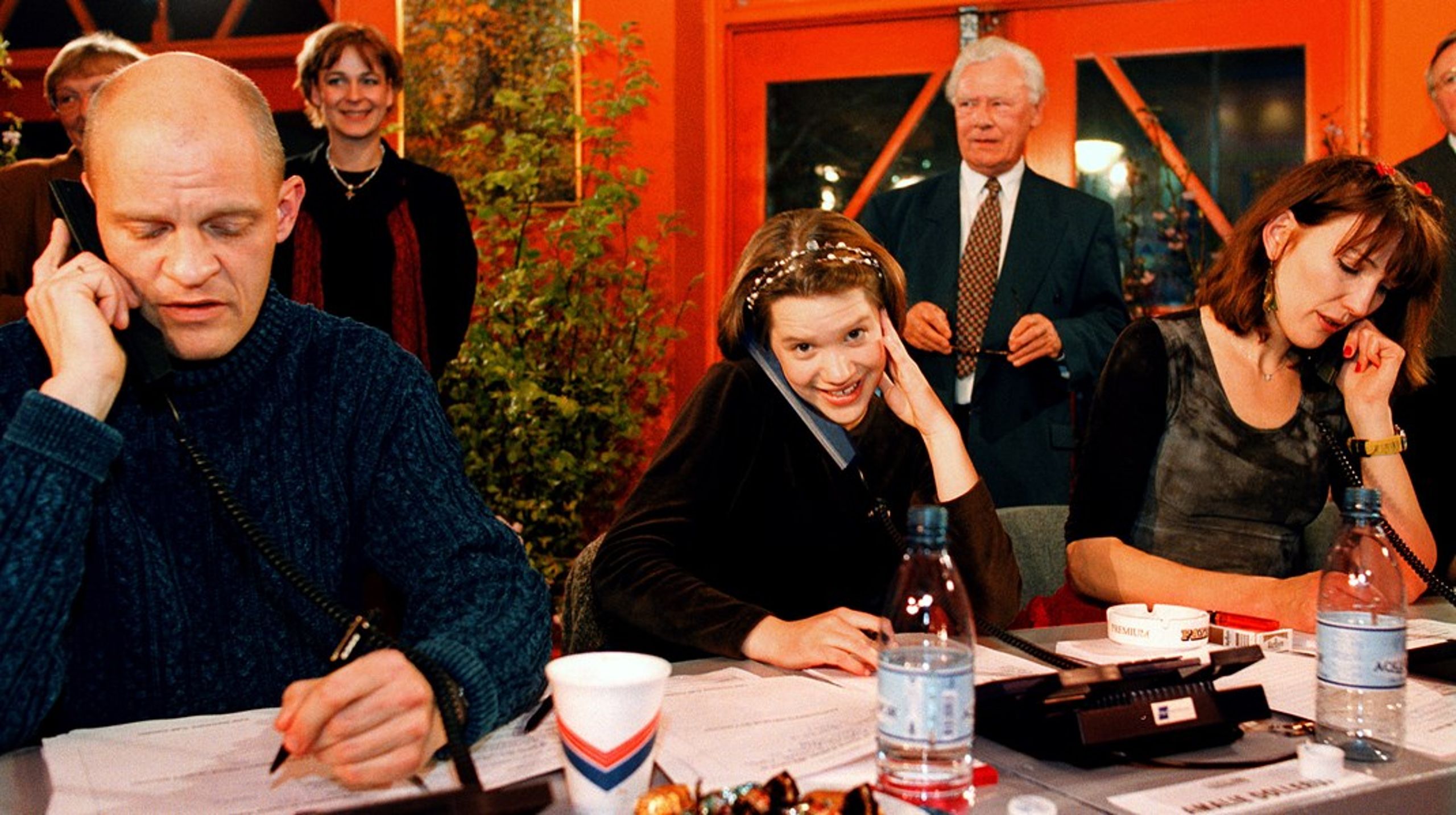 Lars Bom, Amalie Dollerup og Andrea Vagn Jensen besvarer opkald om donationer under DR og TV2s første fælles indsamlingsshow 'Hjælp Balkan' i 1999. I baggrunden ses tidligere statsminister Poul Schlüter.