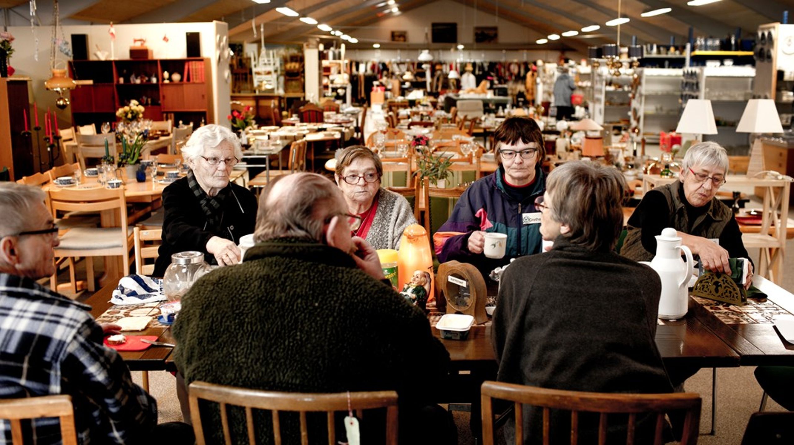 De frivillige i genbrugsbutikken i Helved i Sønderjylland holder frokostpause. Den brogede gruppe af frivillige består primært af førtidspensionister, efterlønnere og pensionister, som vil gøre en forskel for lokalsamfundet.<br>