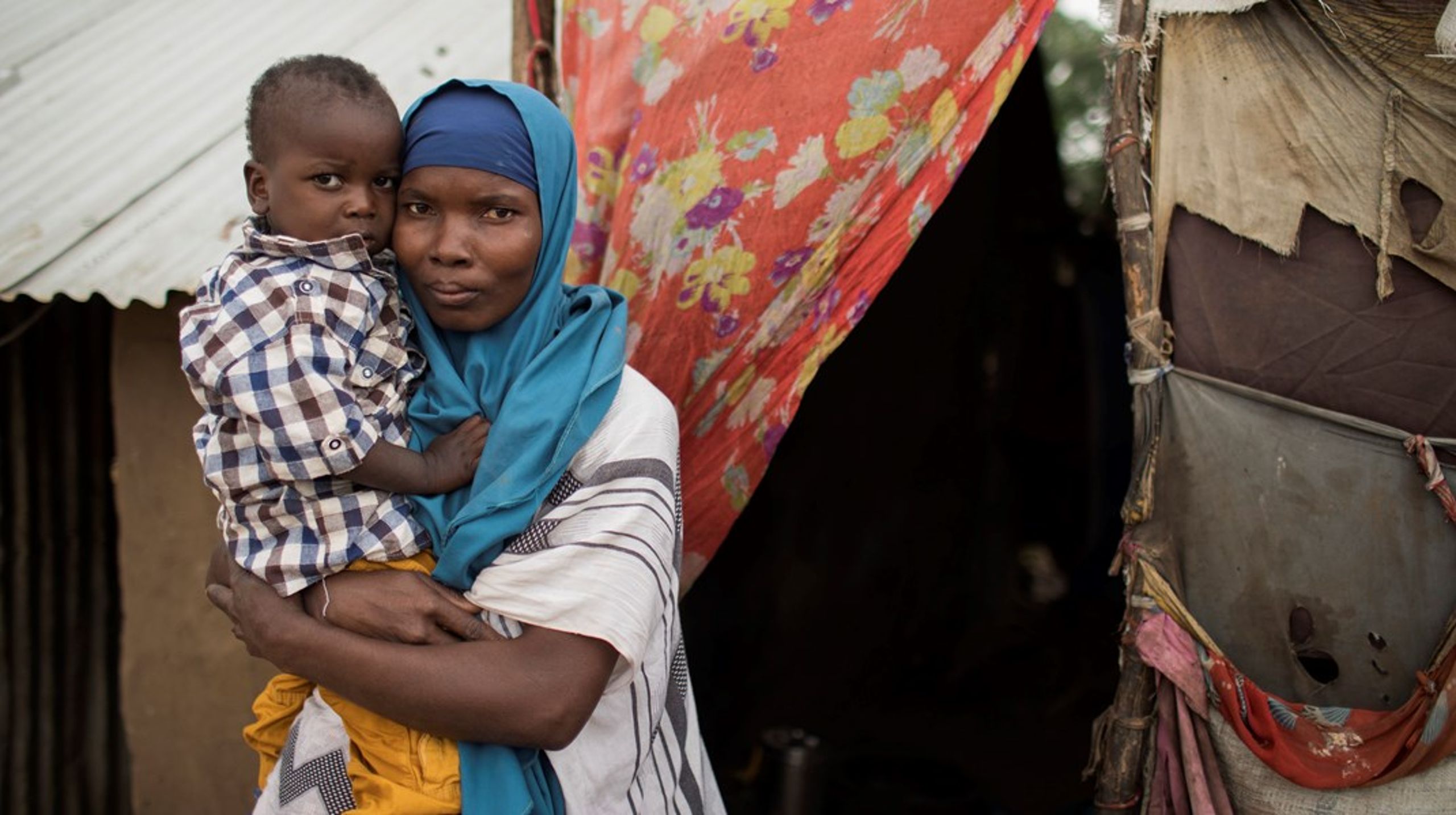 En kvinde og hendes søn foran deres hjem i Kakuma-flygtningelejren i Kenya. I en ny partnerskabsalliance er Danmark gået sammen med Lego Fonden, Grundfos Fonden og Novo Nordisk Fonden om at hjælpe&nbsp;netop Kenya med flygtningesituationen i landet.<br><br><br>